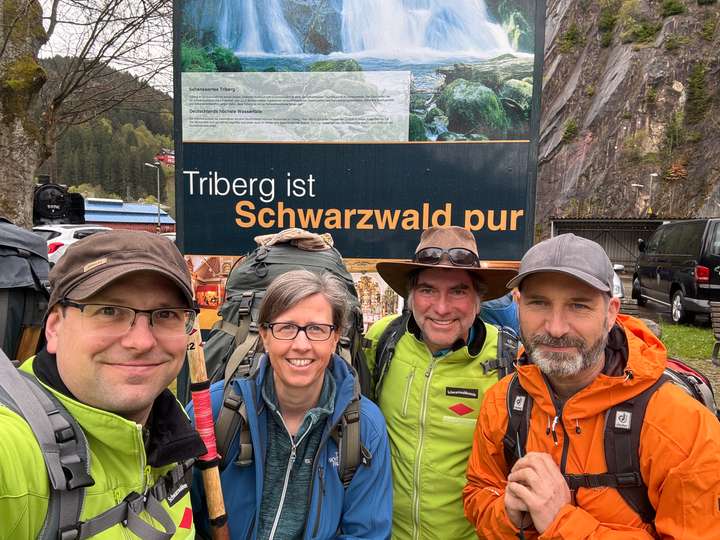 Vier Wanderer vor einem Werbeschild 