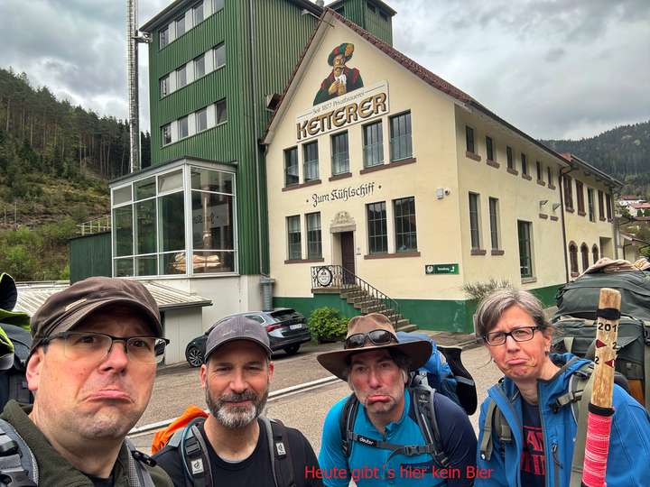 Vier enttäuscht blickende Wanderer, im Hintergrund die Brauerei. Dazu steht 
