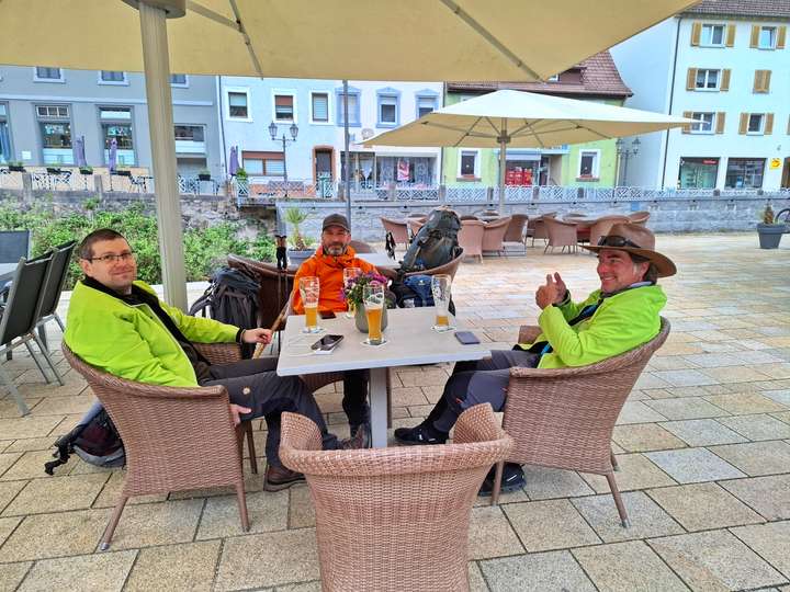 Drei Wanderer sitzen draußen im Restaurant am Marktplatz