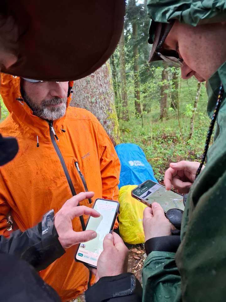 Drei Wanderer schauen auf die Karten im Handy
