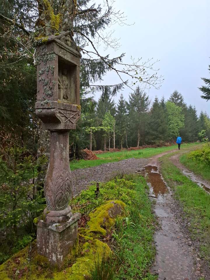 Ein Bildstock, im Hintergrund läuft ein Wanderer